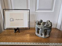 Photo showing the full candle holder to illustrate size and design next to a framed logo on a wooden surface.
