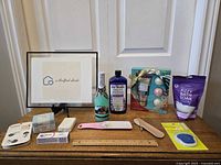 Photo showing assorted bath and cosmetic products including framed sign, foot files, bottle, and bath soak package