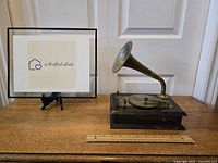 Front view of vintage Enesco gramophone musical jewelry box showing brass horn and wooden base, ruler included for size reference.