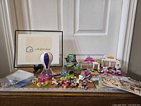 Four Lego Friends sets arranged on wooden surface: Hot air balloon, waterfall play area, pink and white cafe/shop, small vehicle with trailer. Multiple mini figures and accessories visible. Instruction manuals in background.