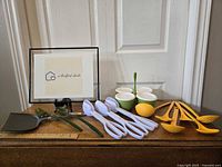 Wide view of all kitchen utensils and Tupperware caddy on wooden surface against white door.