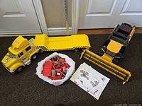 Photo of large yellow Tonka flatbed truck with trailer, farm vehicle, and bag of red building bricks with instructions.
