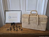 Wicker picnic basket next to black metal ant appetizers.