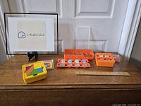 Photo of Osmo interactive learning game pieces including a yellow tangram case and multiple orange trays with various illustrated tokens and game pieces.