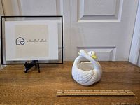 Photo of entwined swan pair planter placed on wooden surface with ruler for size reference approximately 4 inches wide.