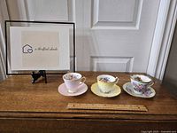 Front view of the three teacups and saucers on a wooden surface with ruler, showing details and size