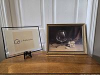 Two framed prints shown, one is a placeholder with brand logo, the other is the vintage framed still life print.