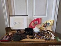 Full lot overview showing all accessories and jewelry arranged on table including fans, sunglasses, jewelry, bags, and trinket dish.