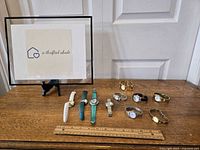 Eight assorted women's watches displayed on a table with ruler for size reference, showing variety in band colors and styles including leather and metal.