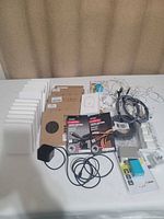 Wide shot of the entire lot showing multiple white wireless charging pads, cables, adapters, and other charging accessories arranged on a table.