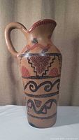 Front view of the hand-painted ceramic water pitcher showing intricate Costa Rican design in red and black on earthy background.
