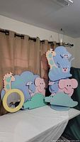 Photo showing handcrafted wooden children's wall mirror with giraffe design, pastel colors, and jungle animal floor lamp featuring elephant, hippo, cats and crocodile stacked figures.