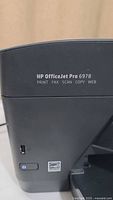 Close-up of HP OfficeJet Pro 6978 model label showing print, fax, scan, copy, web functions.