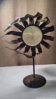 Front view of the metal sun face candle holder on a stand, showing detailed facial features and wavy sun rays.