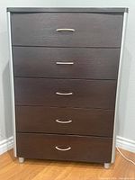 Front view of dresser showing five drawers with silver handles and dark brown wood finish with silver side accents.