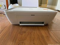 Front view of HP DeskJet 2755e printer showing paper input and output trays and white/gray exterior.