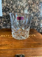 Close-up photo of one Marquis By Waterford Markham whiskey glass with traditional cut crystal pattern and etched starburst base, branded label visible.