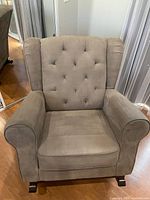 Front view of the gray nursery rocking chair showing tufted back and padded armrests.