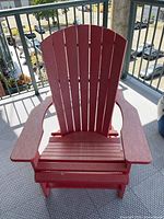 Front view of the red Adirondack chair showing slatted seat and backrest with wide armrests.