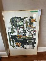 Front view of the framed artwork showing a market scene with fruit, signs, and figures in an abstract illustrative style.