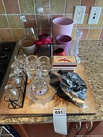 Overview of various glass and ceramic candle holders, vases, and decorative items arranged on a kitchen counter.