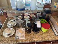 Wide view of several cups, grinders, canisters, and storage containers on kitchen counter