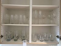 Full view of two shelves with multiple glassware sets including crystal cut glasses and stemmed wine glasses.