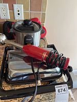 Photo showing Hamilton Beach electric grill, Allegro small crock pot, Cuisinart Smart Stick hand blender with coiled cord, and red oven mitts on a kitchen counter