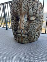 Front view of large carved face mask with leafy vine carving and weathered finish