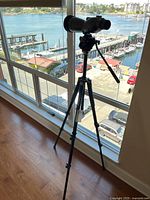 Full setup of spotting scope mounted on tripod near window