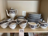 Overview of entire set on shelf showing stacks of plates, bowls, cups, coffee pot, creamer, sugar vessels