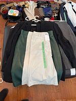 Photo showing a black blazer, a black and off-white skirt or pants with belt loops, various scarves, belts, and bags arranged on a surface.