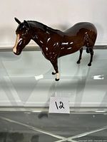 Front angled view of the brown ceramic horse figurine with white markings on front legs and muzzle.