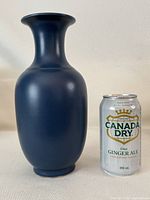 Chinese blue glaze porcelain vase next to a 355 ml soda can for size comparison. Matte blue finish with a traditional rounded vase shape and flared neck.