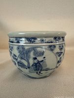 Front side showing a figure holding an object under a tree with flowers around the circular panel.