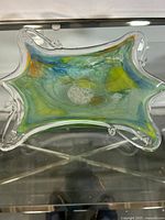 Top-down view of the art glass plate showing its multicolored swirl design and curved edges.