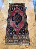 Full view of the Mazlaghan carpet showing the geometric pattern and central medallion on a tiled floor.