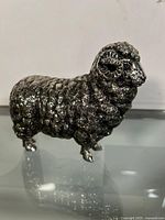 Front and side view of the metal sheep figurine showing detailed texture and curled horns.