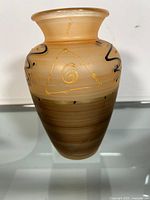 Front view of the Murano glass vase showing gold spiral within triangular motif and black swirls on amber gradient glass