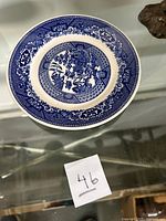 Top-down view of blue and white vintage Royal Blue Willow patterned ceramic plate showing detailed design and size.