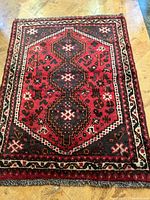 Full view of red three‐medallion Shiraz rug laid flat on floor