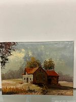 Full view of the signed oil painting on canvas showing a rustic house with red roofs, trees and sky