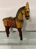 Front right angle view of the hand painted wooden horse figurine showing detailed paintwork on the body, legs, and head.