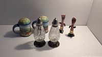 Three sets of salt and pepper shakers displayed: ceramic mug style, cut glass with metal, and wooden novelty characters