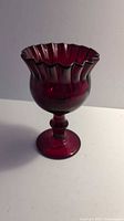 Amber colored glass goblet shown from angled side view, highlighting ruffled rim and thick glass construction
