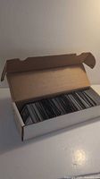 Cardboard box open and filled with tightly packed Magic: The Gathering cards seen from the top.