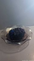 Ruffled edge iridescent carnival glass dish with detailed glass grape cluster on top.