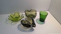 Four green glass pieces on a white surface for full lot overview.