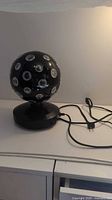 Full view of black rotating disco ball on a black base with power cord.