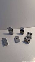 Lot of 7 various metal lighters displayed on a white surface, some open.